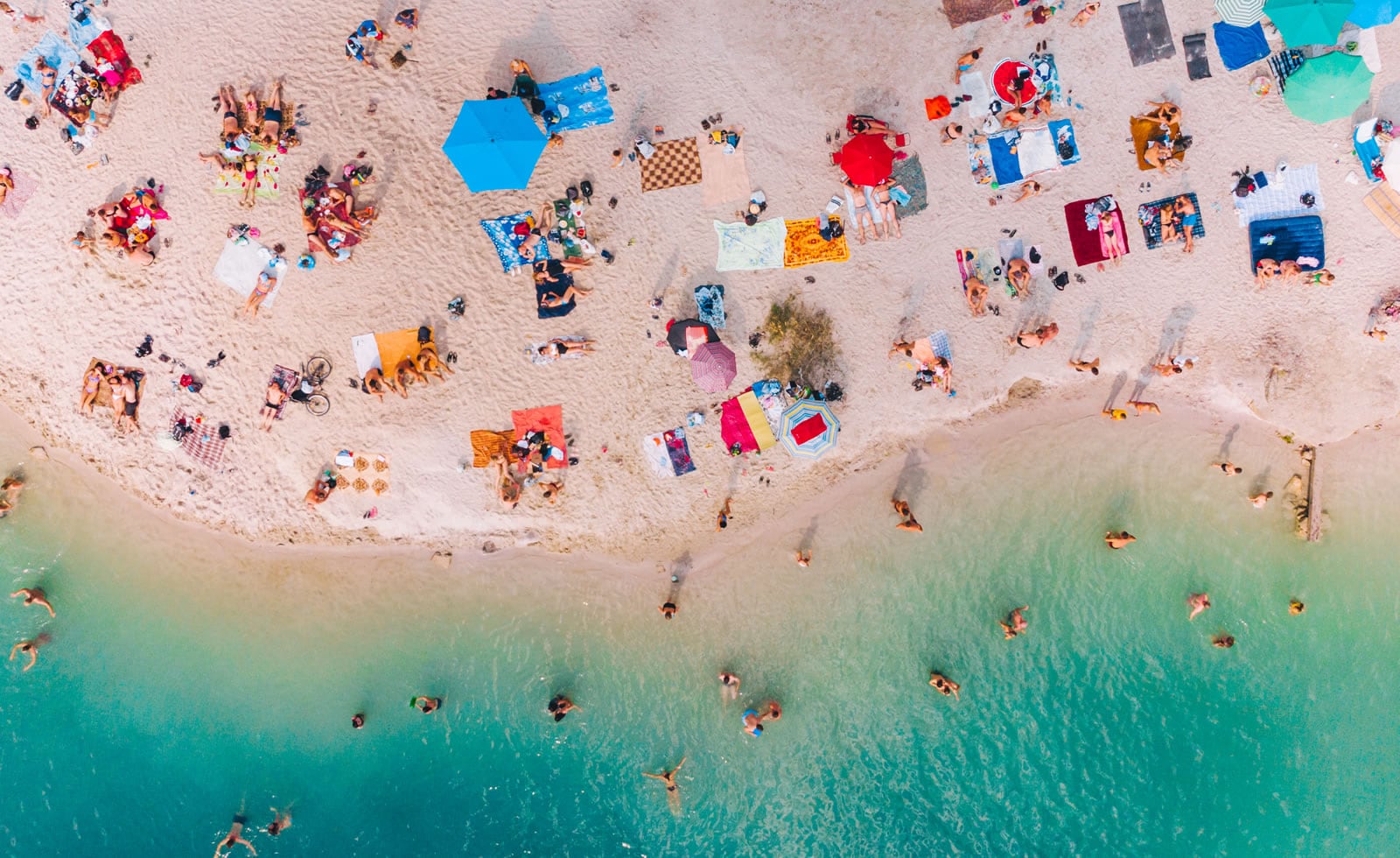 Aerial view of tourists and sun loungers on a sunny beach